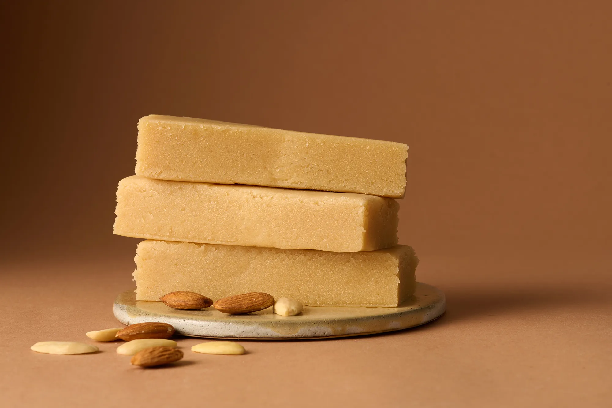 Stimmungsbild: Marzipan Rohmasse mit Mandeln auf braunem Hintergrund